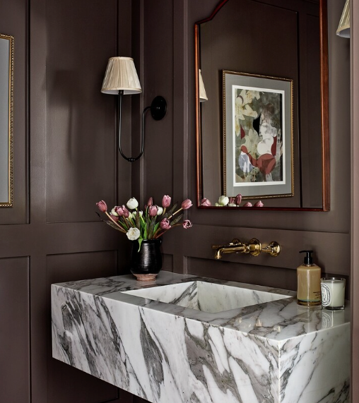 A bathroom with chocolate brown walls and a marble floating sink.
