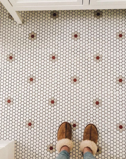 Mosaic tiling with a flower pattern and slippered feet standing on it.