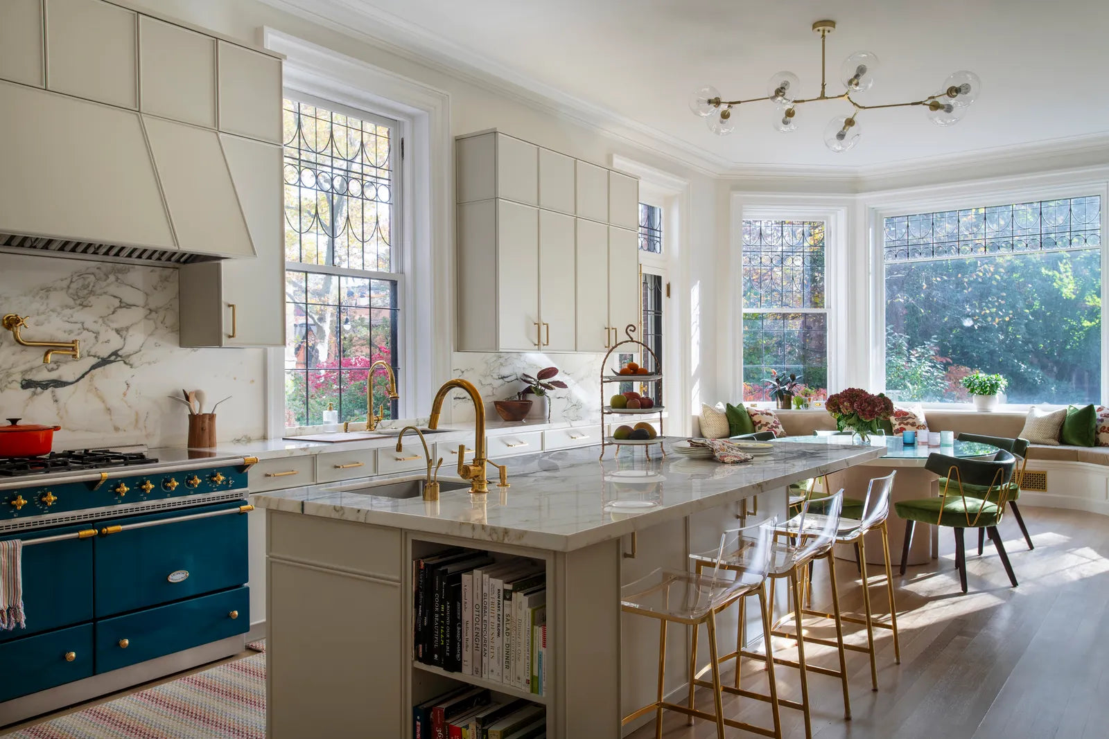 A large kitchen with a marble kitchen island and bay window dining area. 