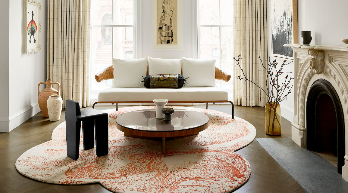 A living room with an eclectic rug, round coffee table and white sofa. 