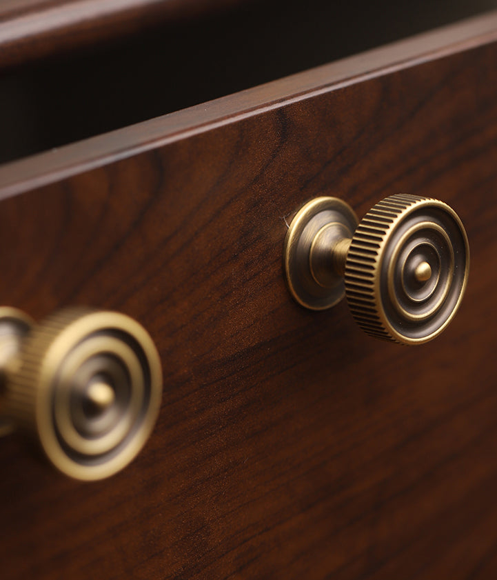 A close up view of 2 brushed bronze drawer knobs. 