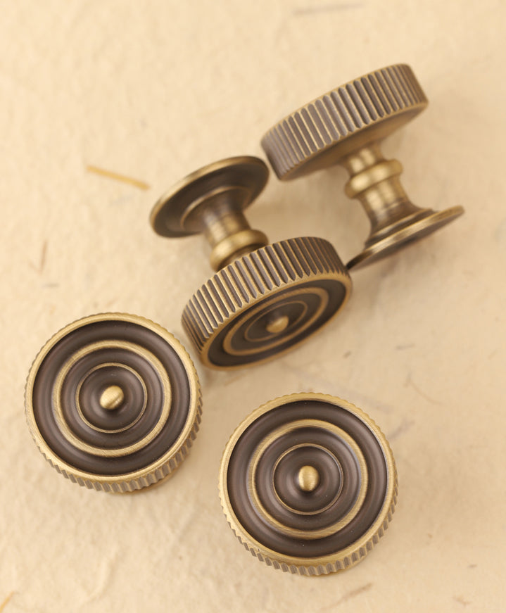 4 drawer knobs in an antique brass finish showing the top view and bot sides. 